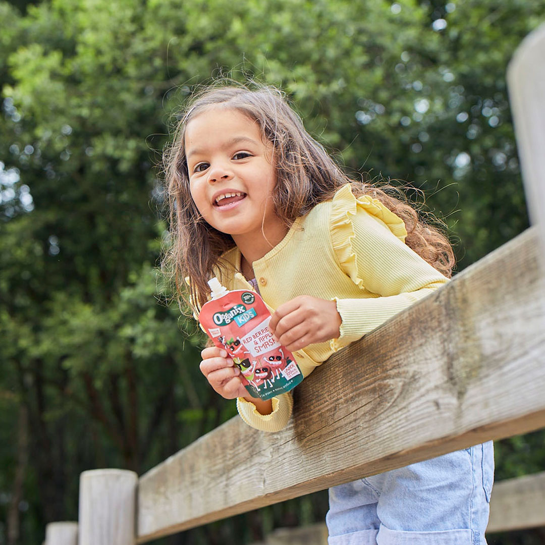 Young girl leaning on fence with Organix Pouch