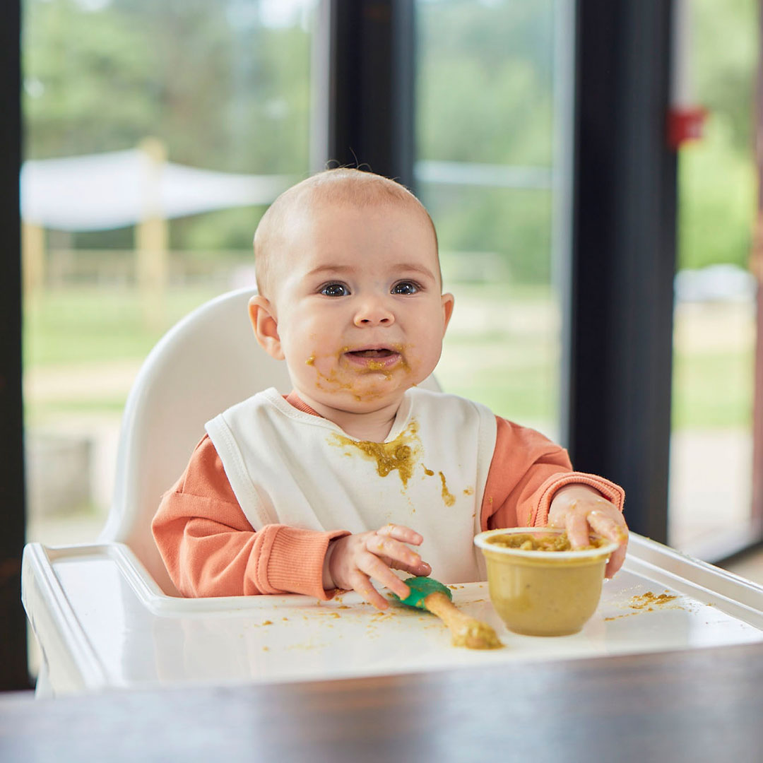 Baby in high chair, eating a meal
