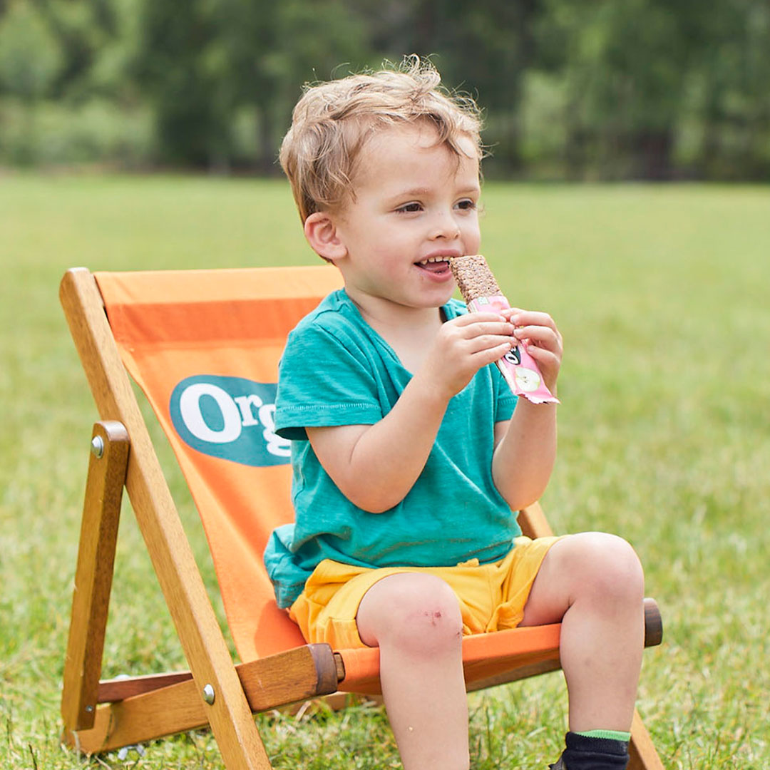 Boy on deck chair, eating oaty bar