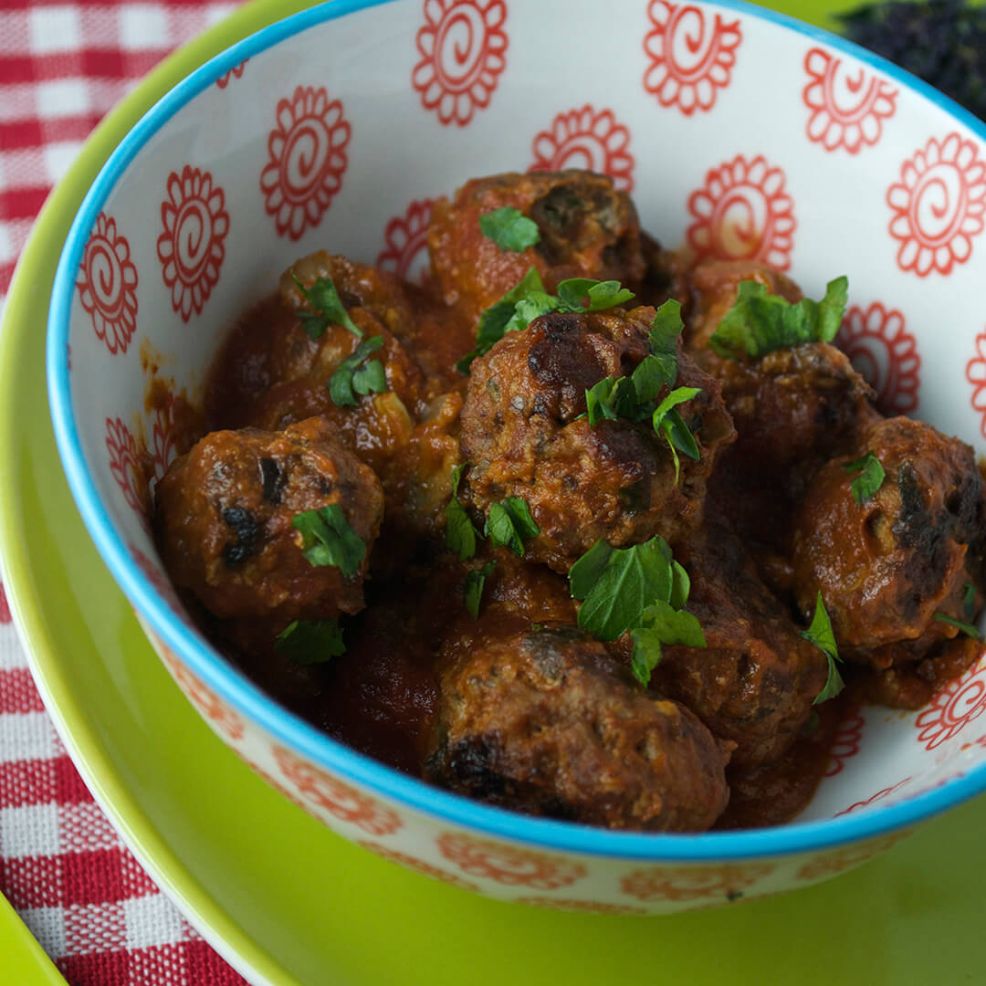 A bowl of meatballs topped with fresh herbs