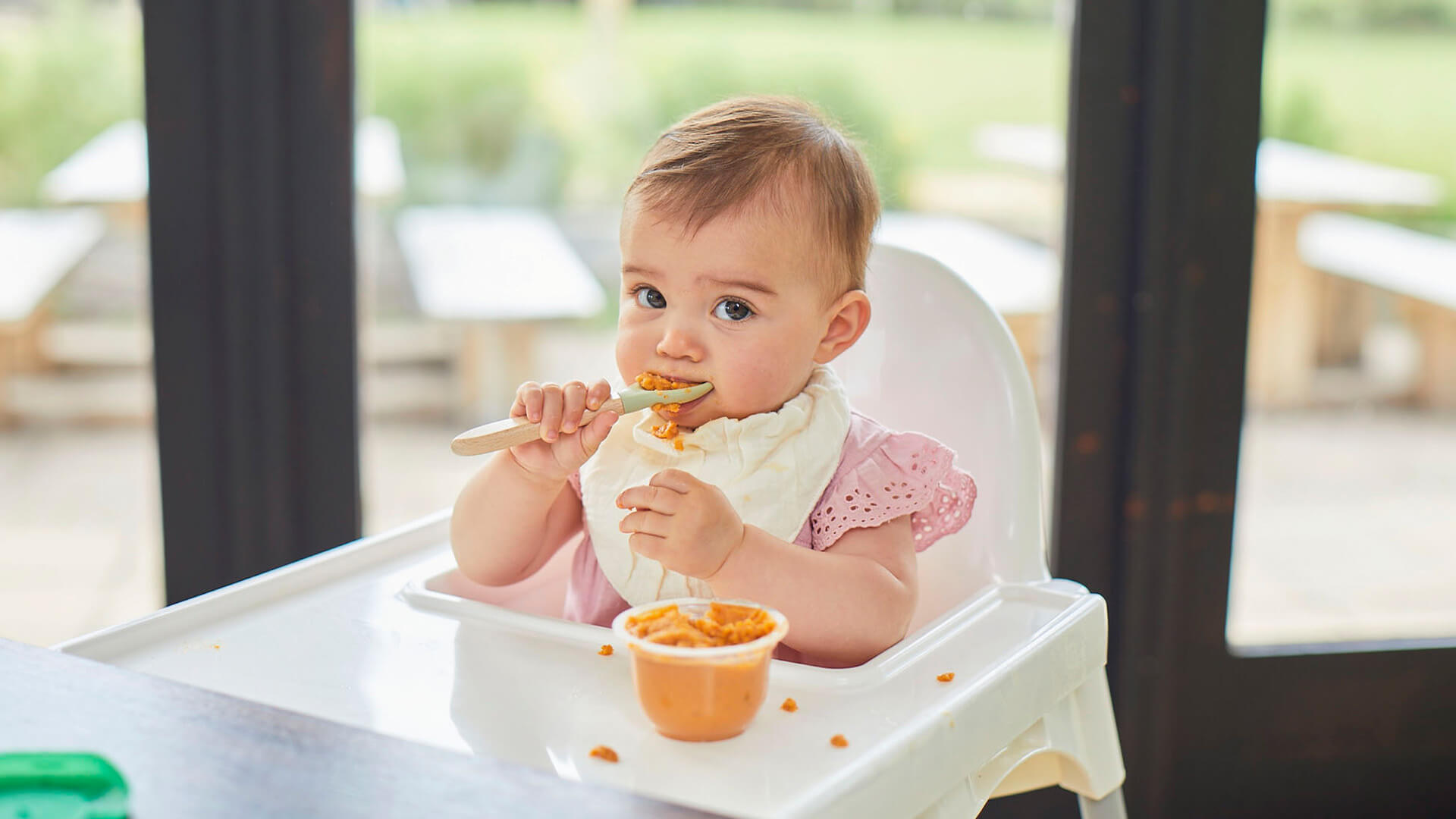 A baby sitting on a high chair and eating