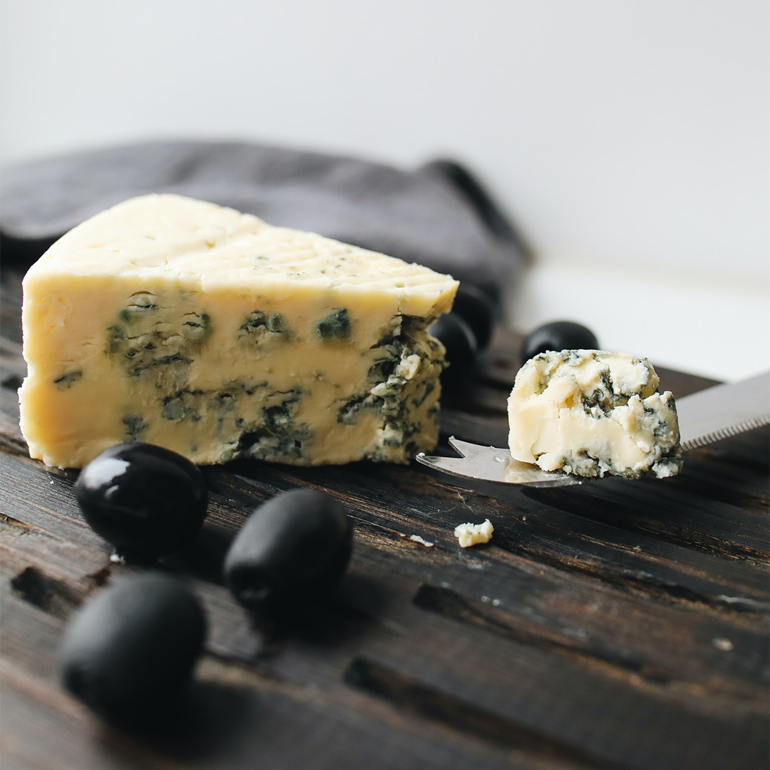 A slice of blue cheese next to some olives