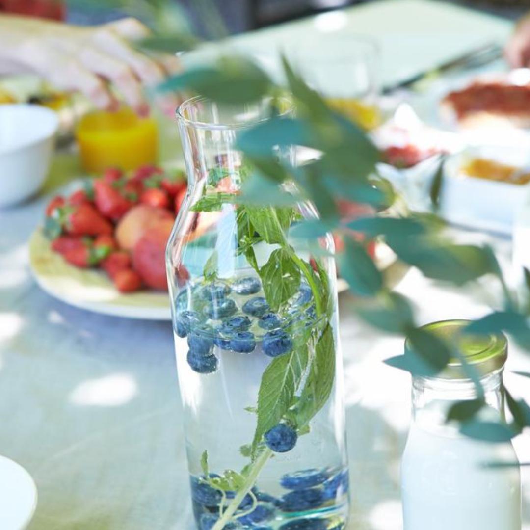 Table with strawberries, a glass jar with water, blueberries and mint leaves, a bottle with milk