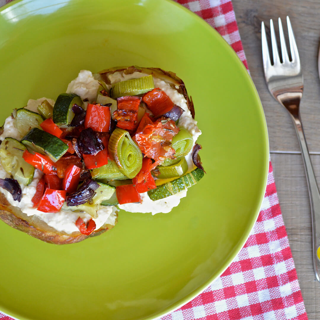 Jacket potato topped with hummus, courgette, red pepper, red onion, leek and cherry tomatoes