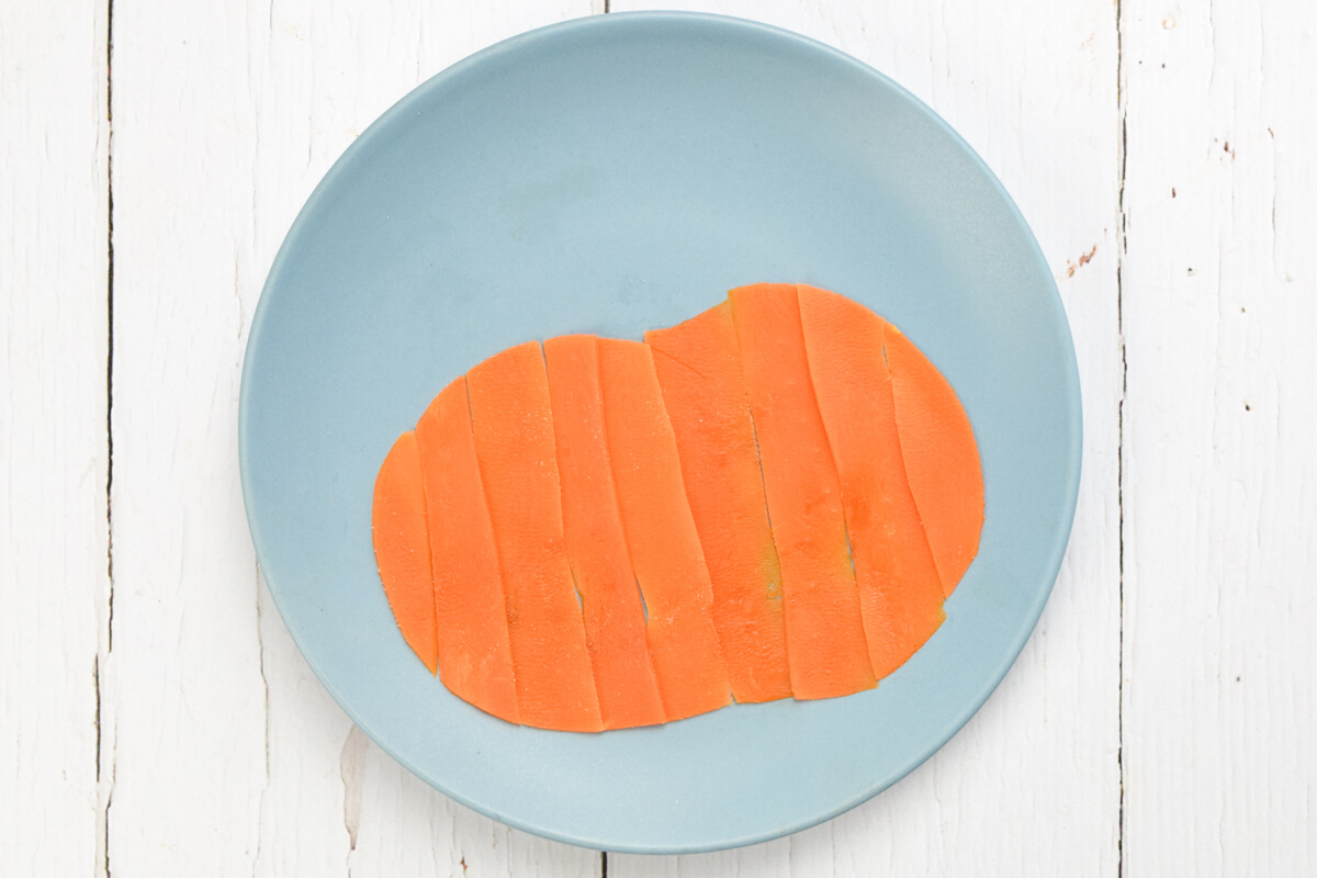 A blue plate with steamed carrot slices shaped into a pumpkin. 