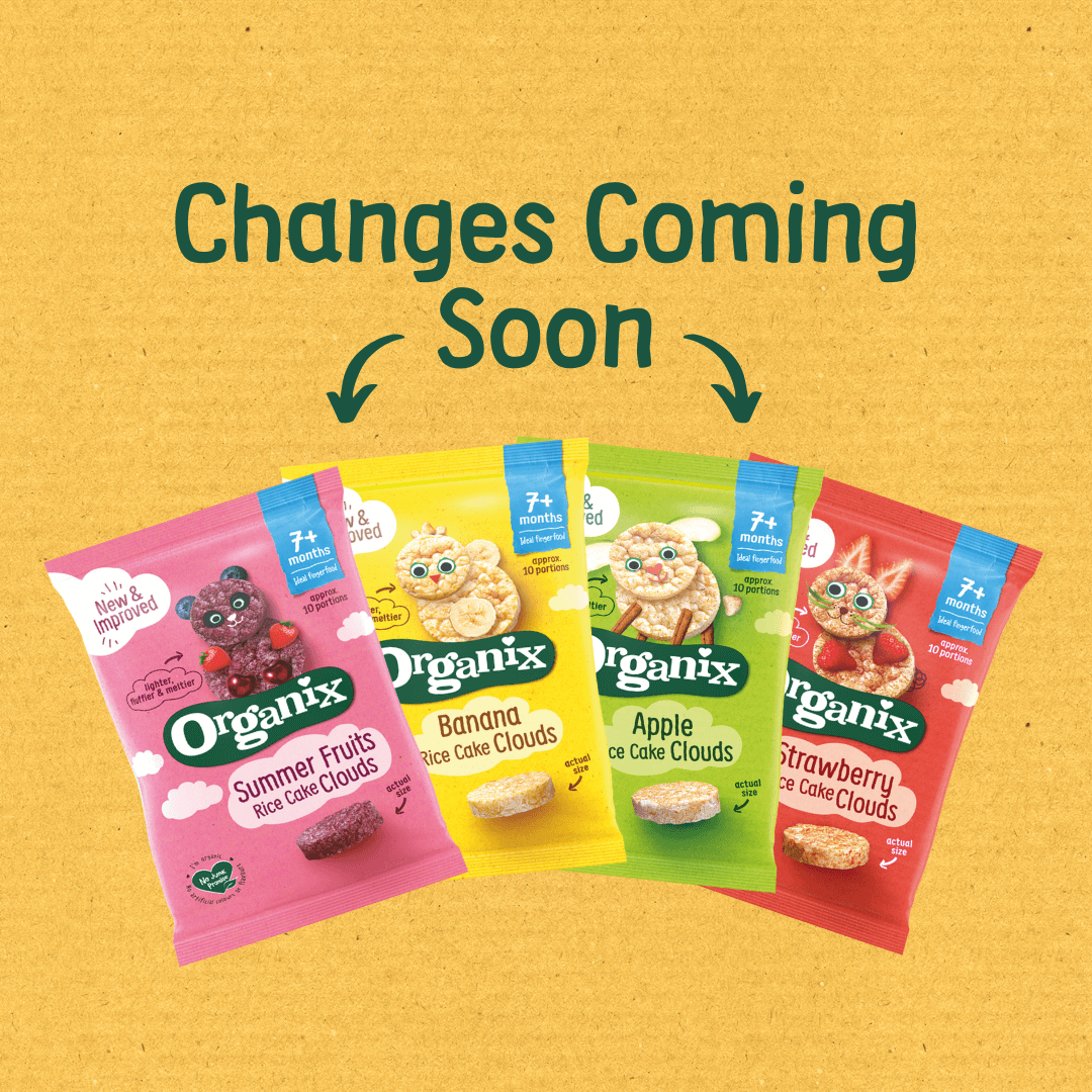 Four colourful packets of Organix Rice Cake Clouds snacks displayed against a textured yellow background. The flavors shown are Summer Fruits (pink packet), Banana (yellow packet), Apple (green packet), and Strawberry (red packet). Each packet features playful fruit characters and the text “7+ months” and “New &amp; Improved.” Above the packets, bold green text reads “Changes Coming Soon” with two arrows pointing downward toward the products.