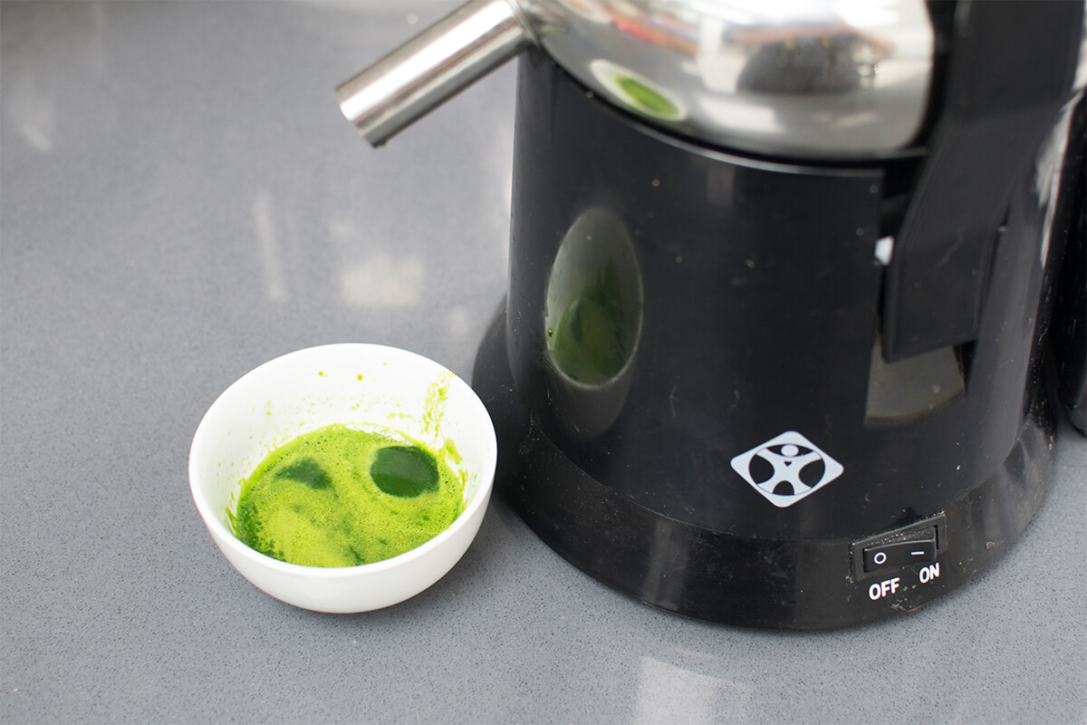 A juicer with some spinach juice being made