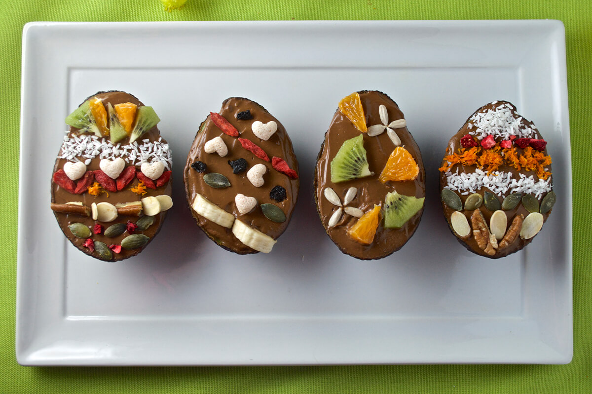 4 Avocado & Chocolate Orange Easter Eggs decorated with fruit and seeds