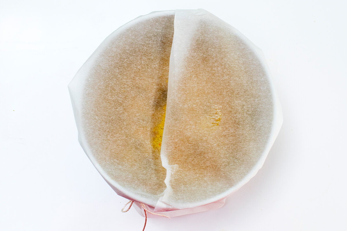 Christmas pudding mix in a bowl, covered with parchment paper