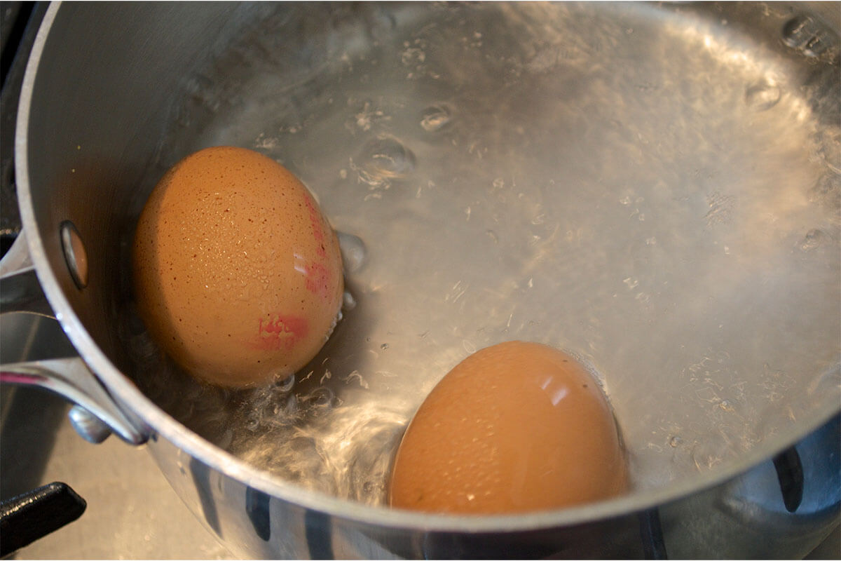 A saucepan of water with 2 eggs being boiled