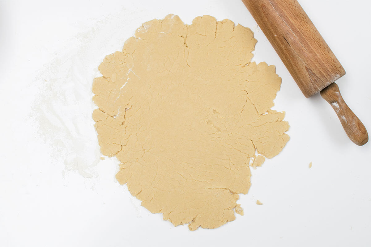 A floured surface with rolled out dough next to a rolling pin