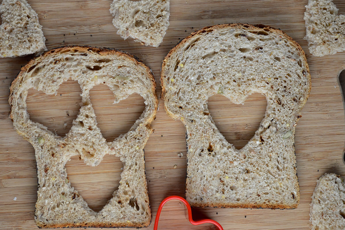 2 slices of bread with heart shaped cut-outs, one with 3 heart shaped cut outs, the other with one
