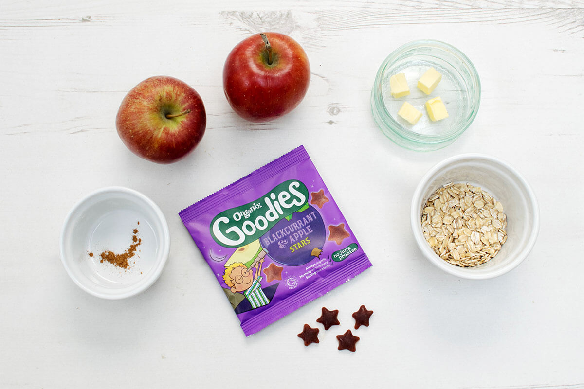 2 apples next to a small bowl of butter cubes, oats, cinnamon and some Organix Goodies