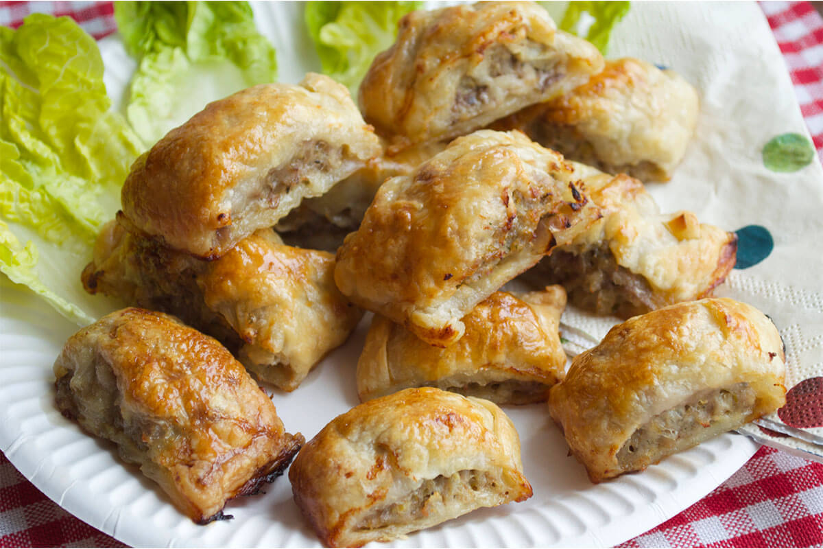 A plate of mini sausage rolls served with some lettuce leaves 