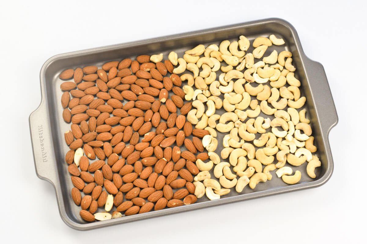 A baking tray with almonds and cashews on it