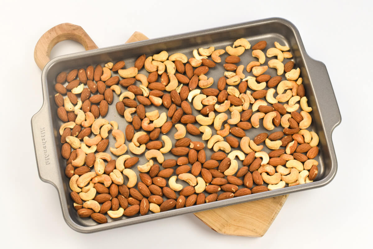 A baking tray with roasted almonds and cashews on it