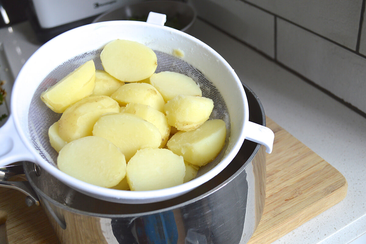 Boiled potatoes being drained over a saucepan