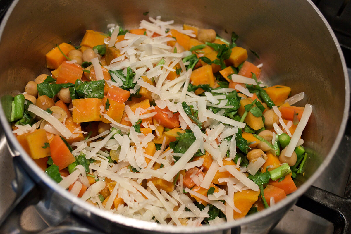 Sweet potato and carrot in a saucepan with asparagus, watercress and parmesan cheese