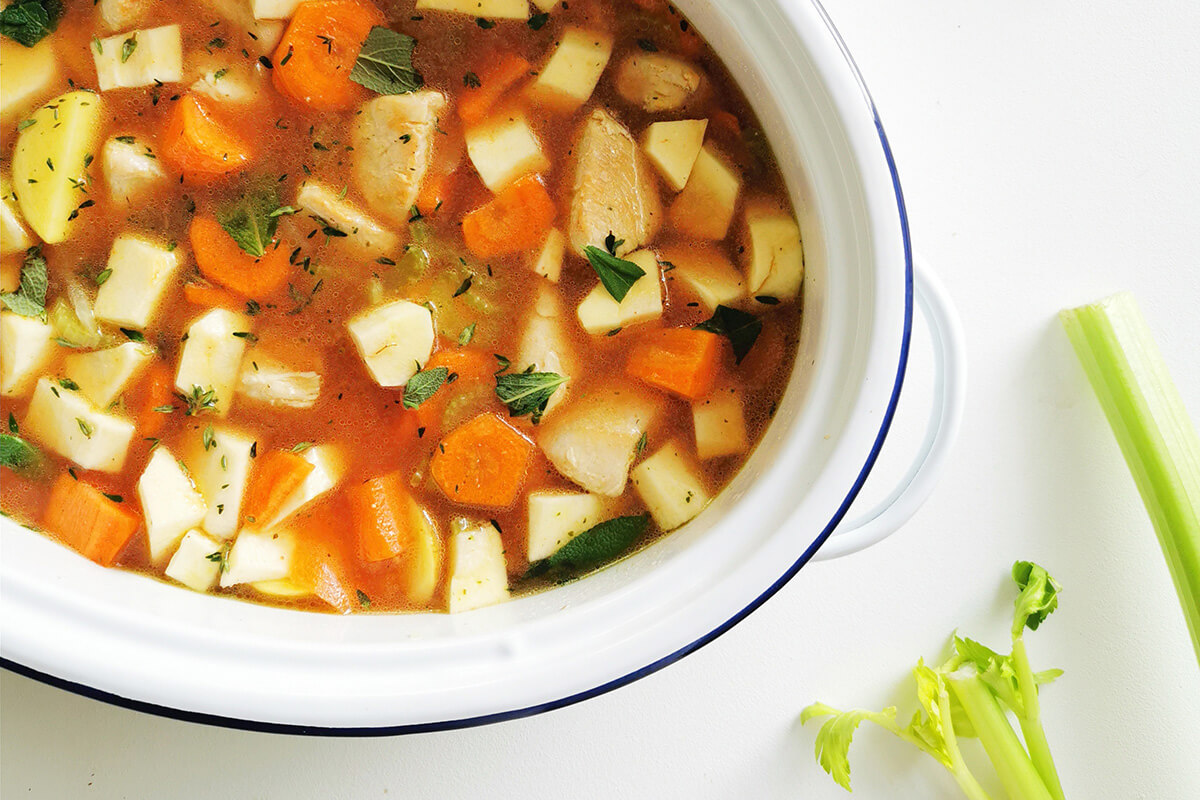 A casserole dish with onion, celery, chicken, stock, potatoes, parsnips, carrots, tomato puree and herbs