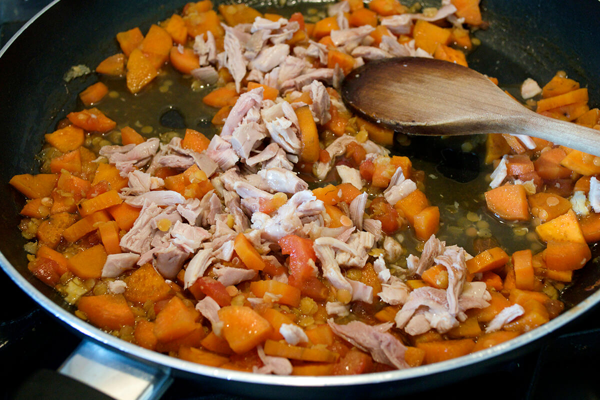 A saucepan of sweet potato, carrot, chicken and lentils being cooked