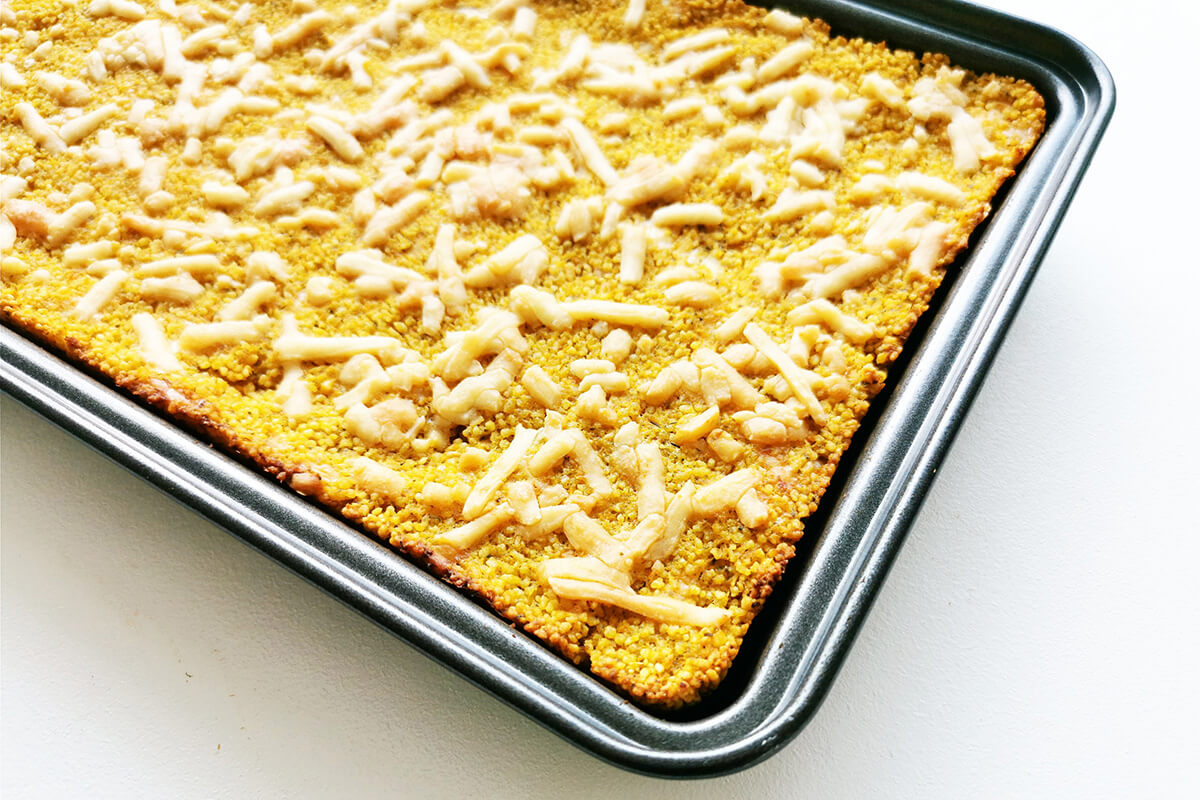 Couscous cooked with vegetable puree in a baking tray and topped with cheese