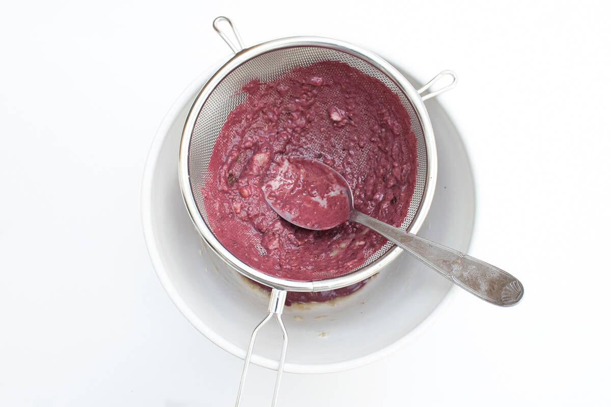 Mashed banana with blackberries, raisins and yoghurt being sieved