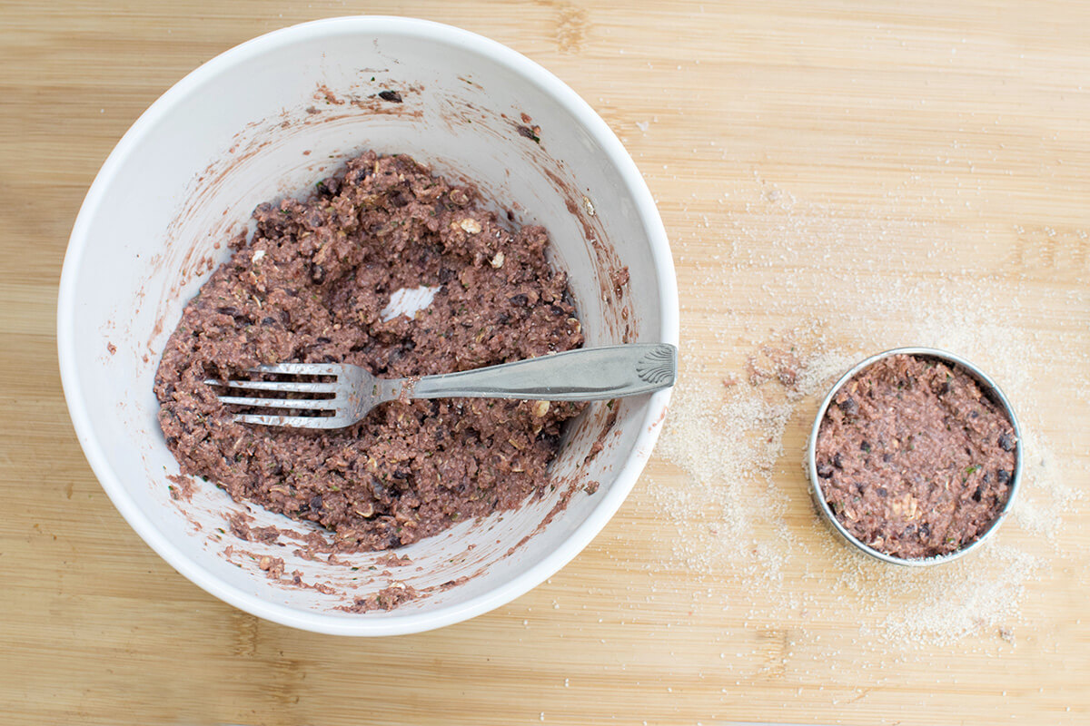 A bowl of beetroot burger mix next to a metal cutter