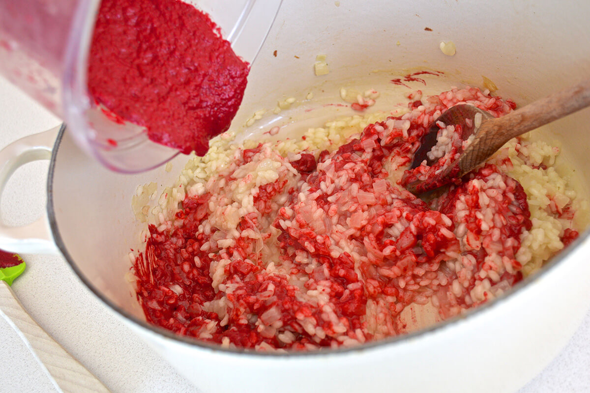 Pureed beetroot being stirred into risotto rice