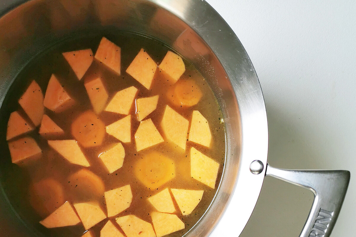 Carrot and sweet potato in a saucepan of vegetable stock
