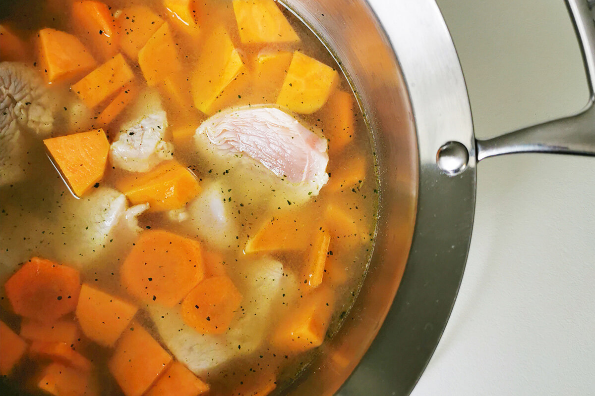 Carrot, sweet potato and chicken in a saucepan of vegetable stock