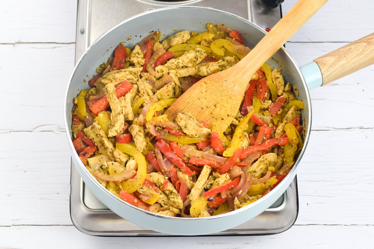 A frying pan with chicken and peppers being cooked