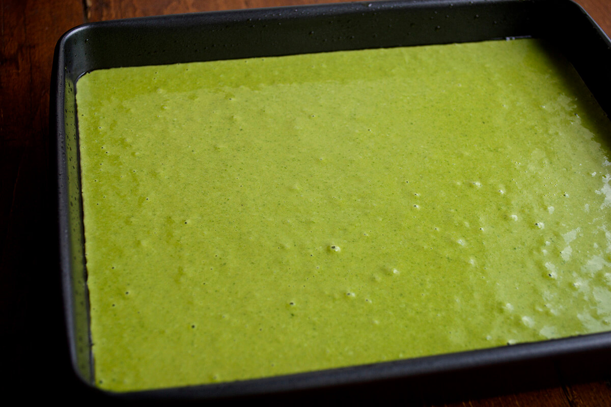 A rectangular baking tin with green tart mixture in it