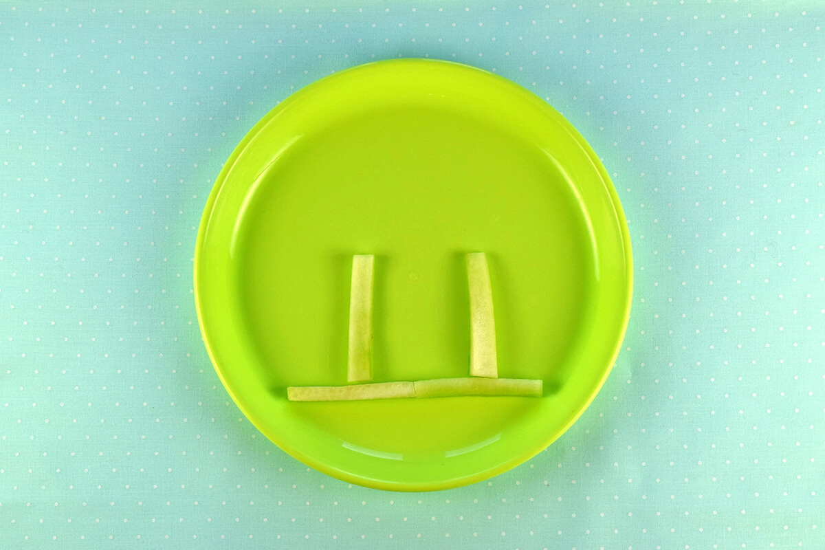 Long cucumber sticked placed horizontally on plate, with two smaller sticks coming up from it vertically
