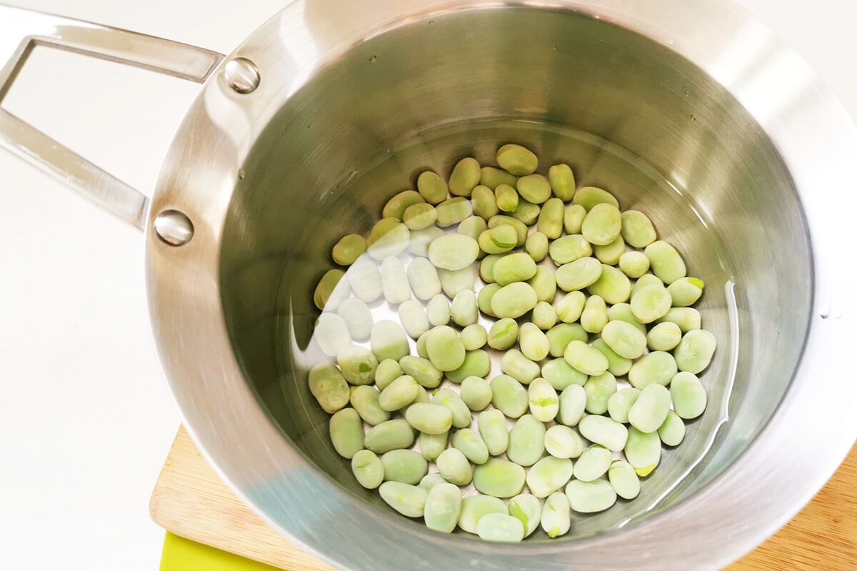 Broad beans in a saucepan of water