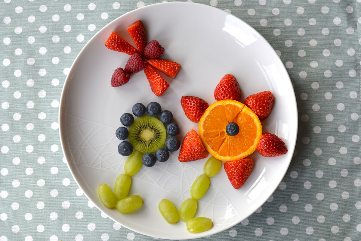 To make dragonfly, 3 raspberries placed above flowers with quartered strawberries on either side for the wings