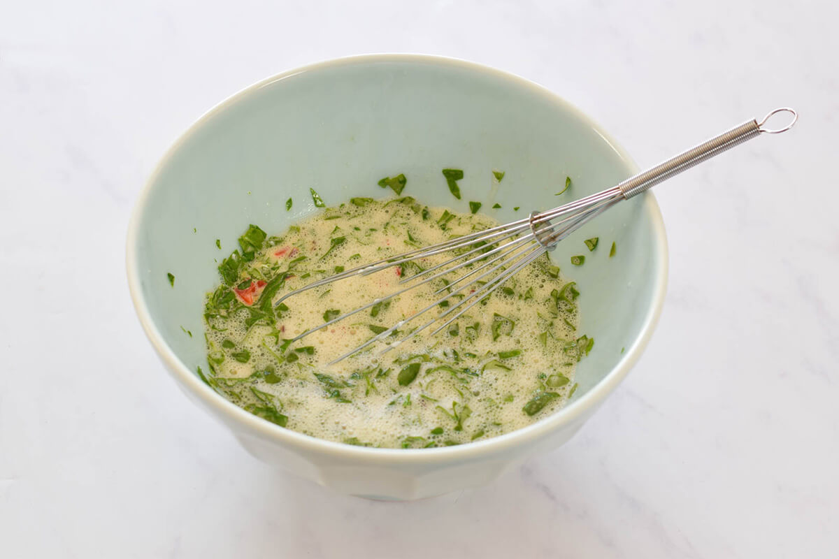 A bowl of eggs with onion, pepper, spinach and goats cheese