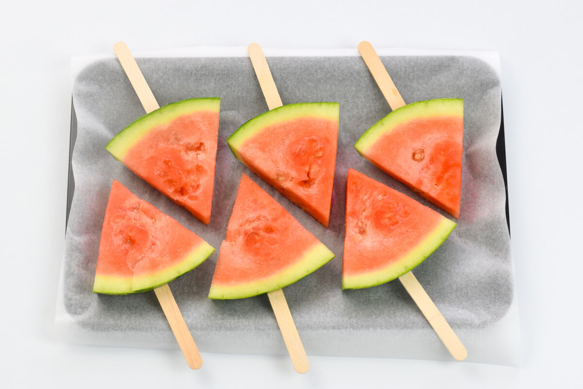 6 watermelon pops on a tray lined with parchment paper
