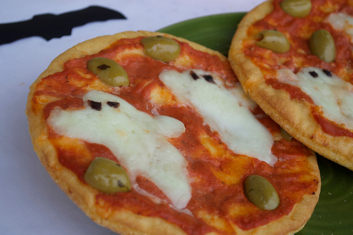 2 pizzas with topped with mozzarella shaped ghosts and green olives