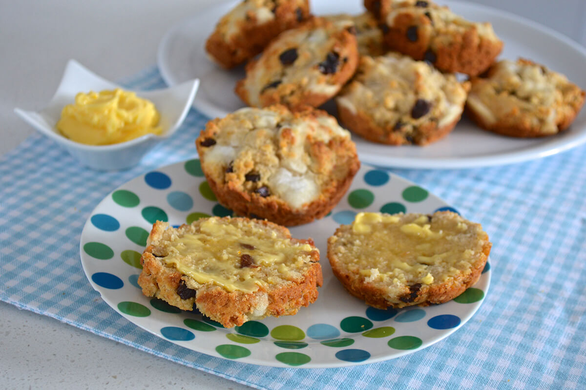 A plate of 3 hot cross muffins next to a plate of more hot cross muffins