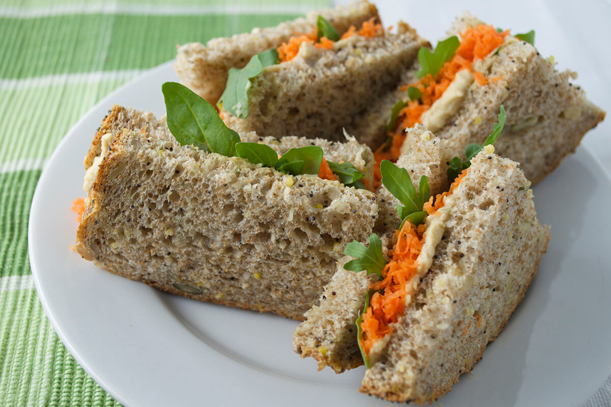 A plate of grated carrot and hummus sandwiches