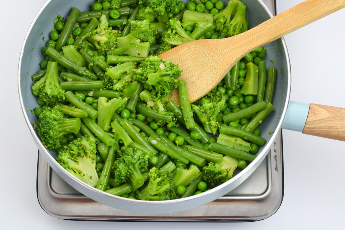 Green beans, peas and broccoli in a pan of garlicky oil