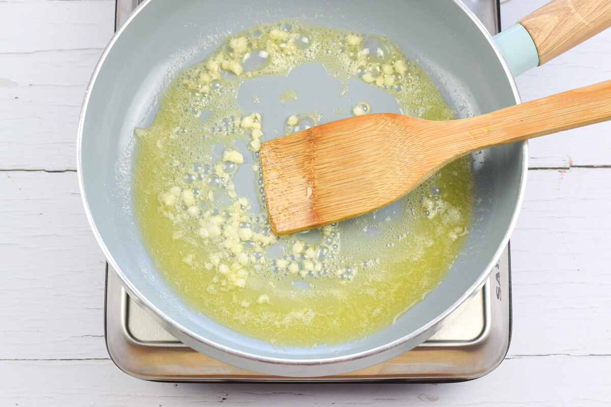 A frying pan with crushed garlic being fried in butter