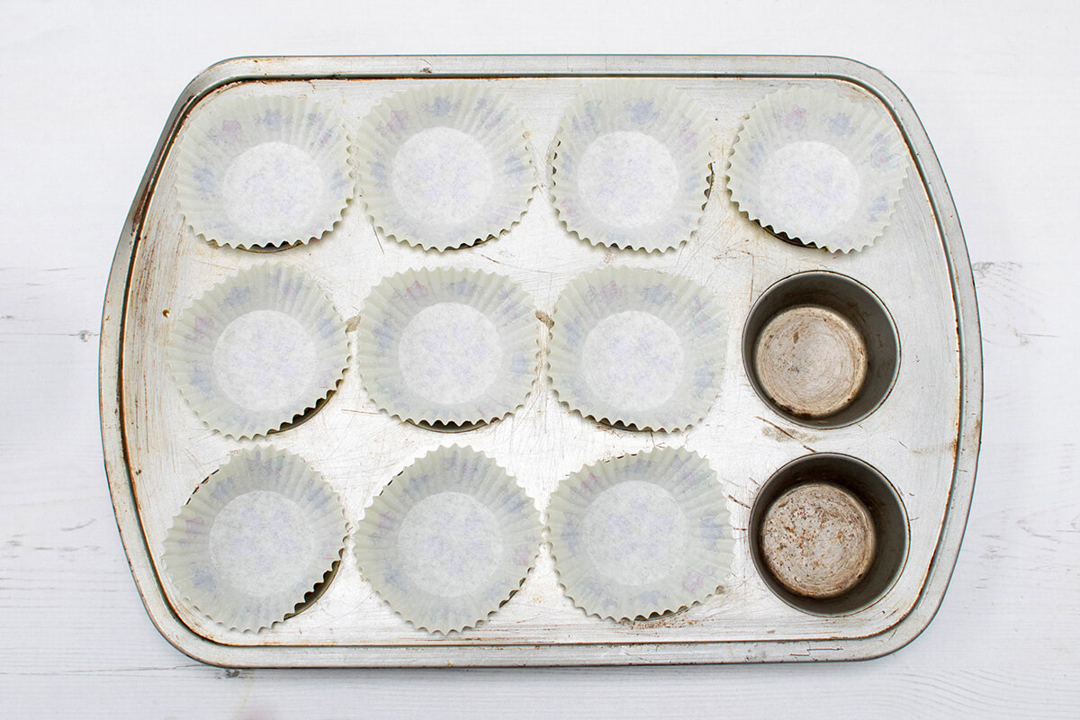 A 12 space cupcake tin with paper cake cases in 10 of the spaces