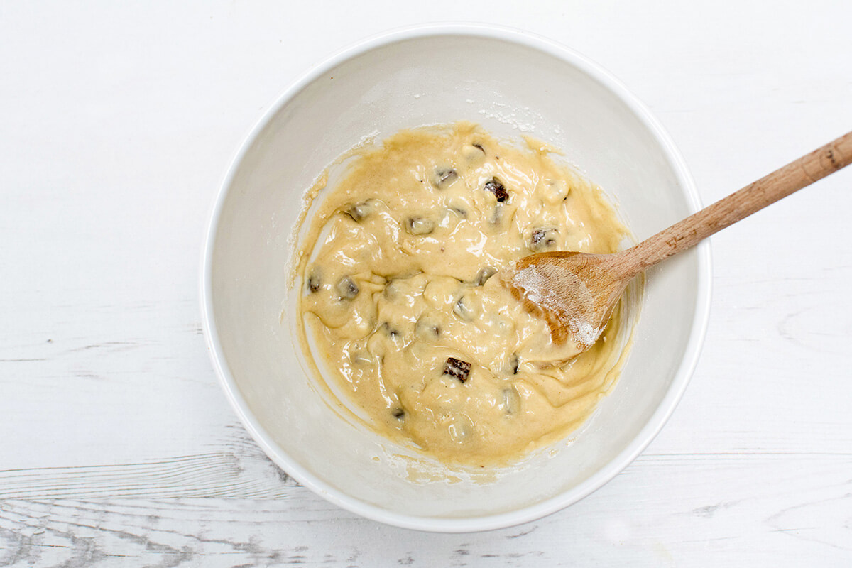 A bowl of cookie mix/batter: oil, egg and honey with flour, banana, orange zest and juice