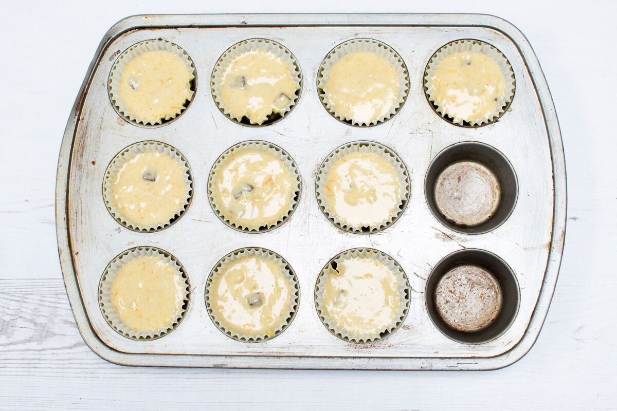 Gummy banana cupcake mixed spooned into paper cake cases in baking tray