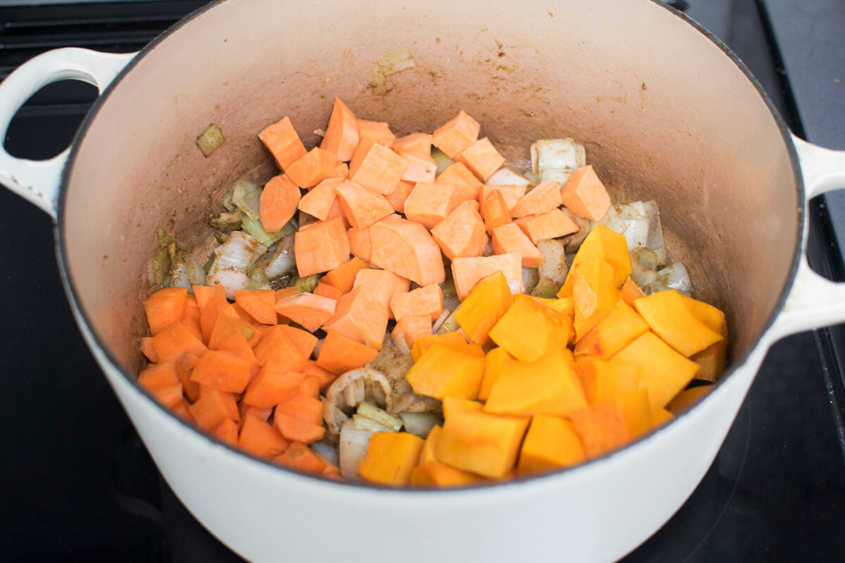 A saucepan with diced leeks, onion, carrots, sweet potato and pumpkin