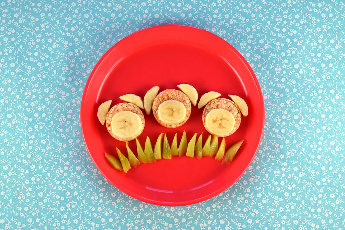 Sliced bananas are placed onto centre of rice cakes. Halved banana slices are above the rice cakes, creating ears