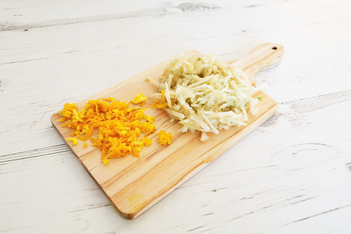 A chopping board with grated apple and orange zest