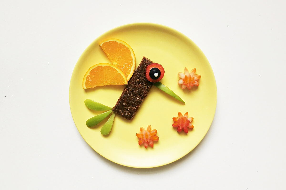 The remaining strawberry slices are cut into flower shapes and placed on the plate to complete the hummingbird oaty bar fun plate 