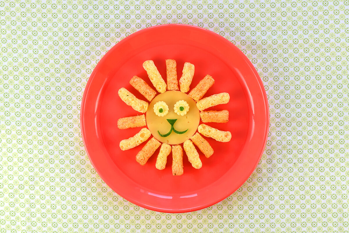Halved carrot sticks and cheese & herb puffs are placed alternating around the cheese circle to create the lion's mane